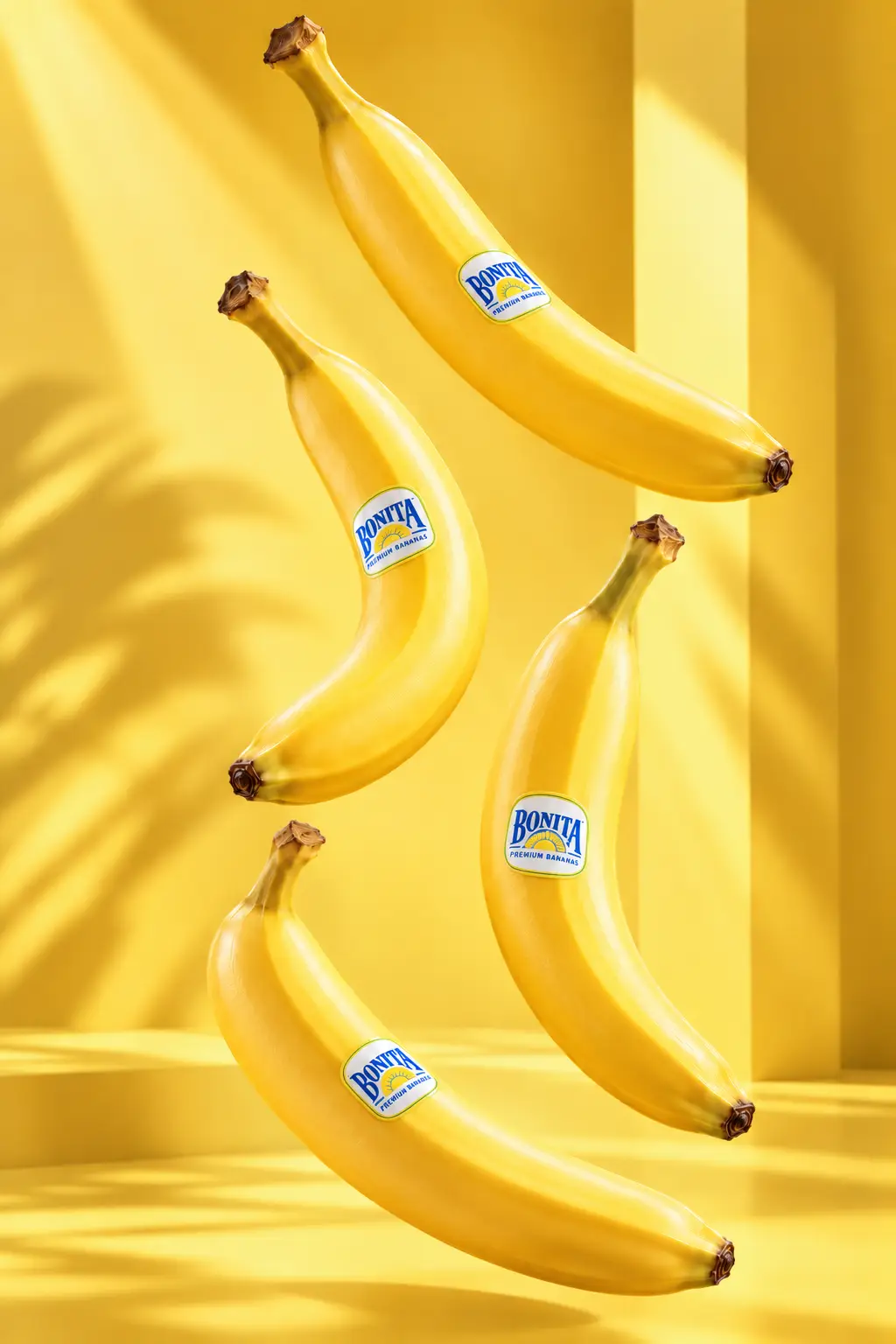 Four yellow bananas with the Bonita sticker, floating on a yellow studio background.